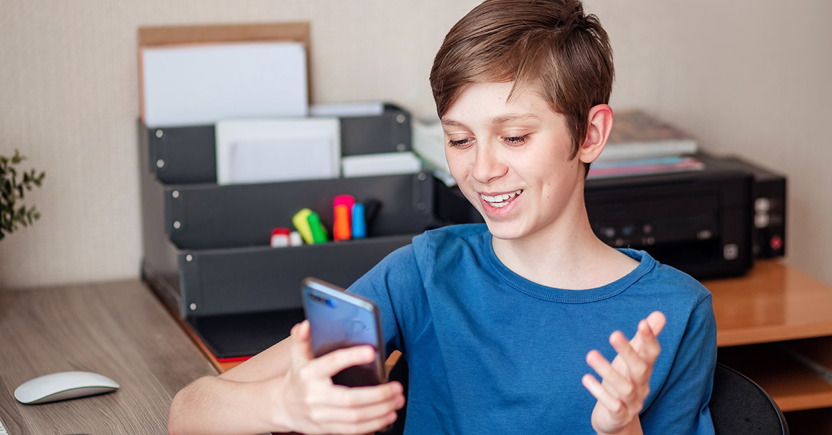 Ein lächelnder Junge hält ein Mobiltelefon in der Hand.